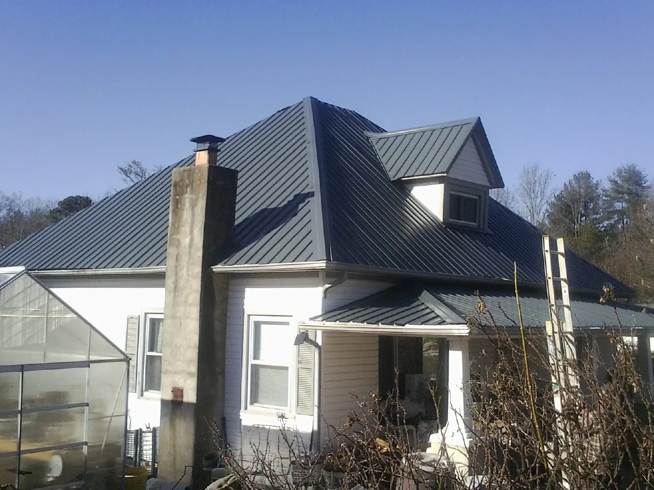Dark blue standing seam metal roof on a white farmhouse with dormer — Slate & Tile Roof Repair by Roofing Brothers in Kyburz