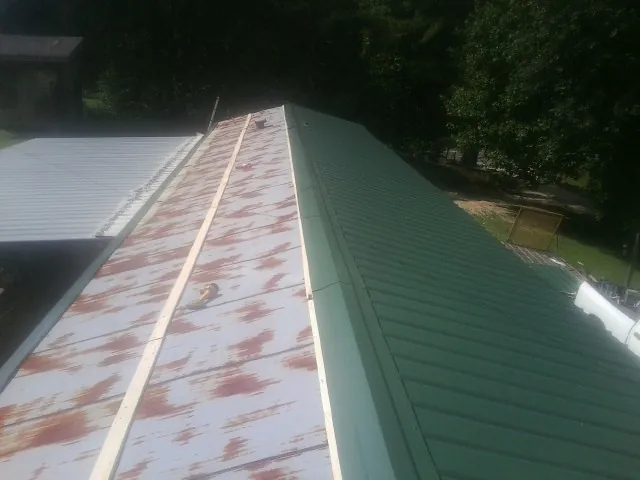 Old rusted panels beside newly installed green metal roofing — Wind Damage Roof Repair by Roofing Brothers in Kyburz