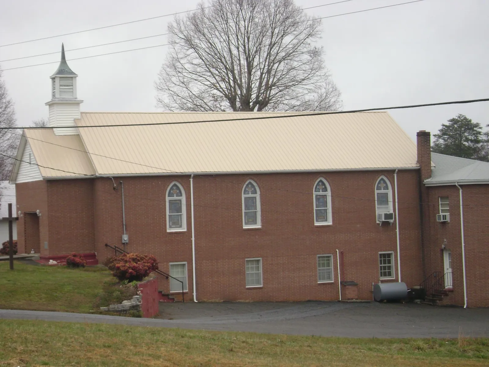 New tan metal roof on a brick church with a white steeple in Kyburz