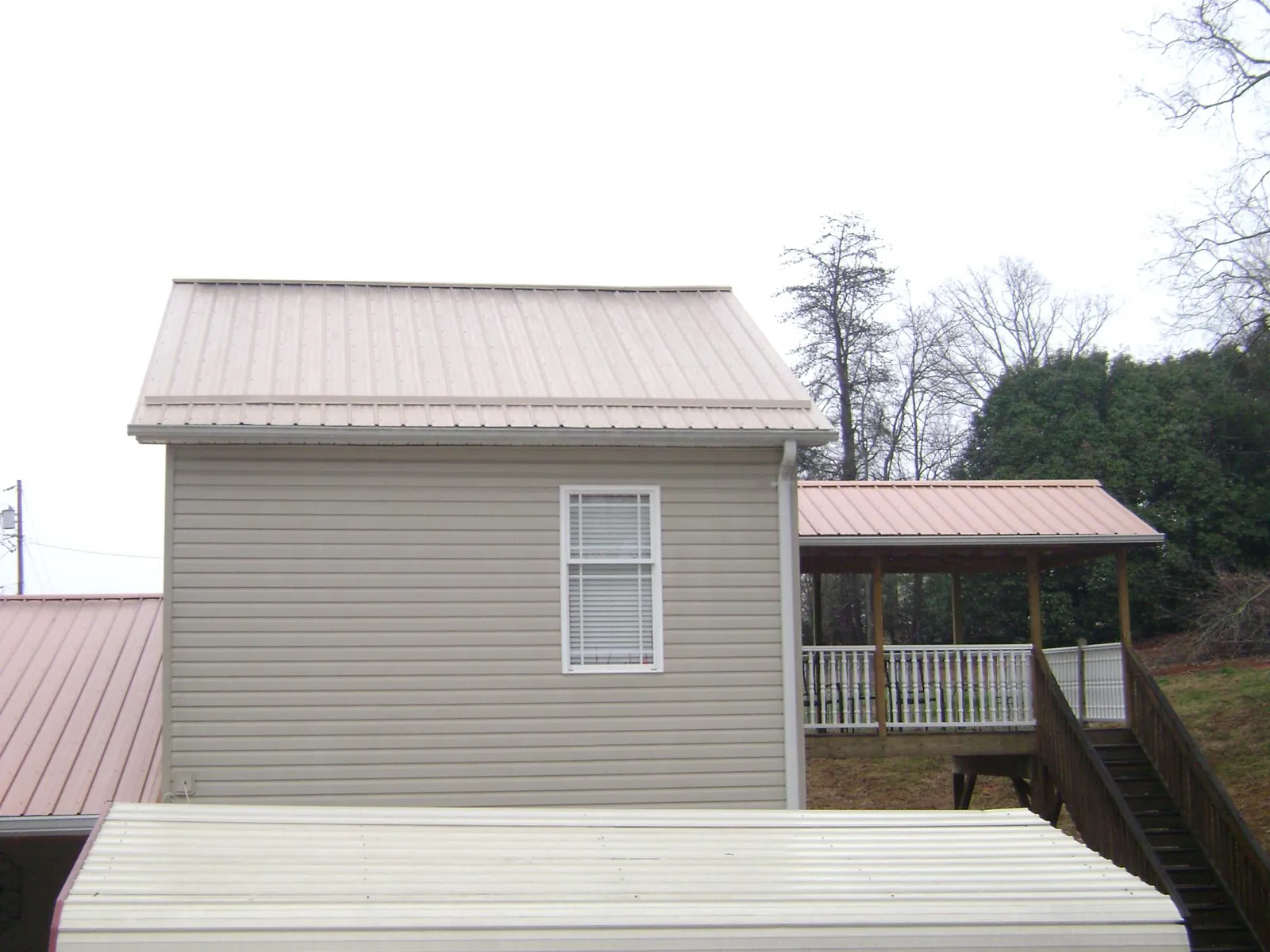 Tan metal roofs on a two story addition and attached porch, from a Roof Replacement job in Kyburz